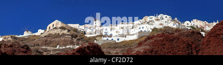 Une vue panoramique sur le village d''Oia et moulin à vent perché sur les falaises rouges au-dessus de la caldera Banque D'Images