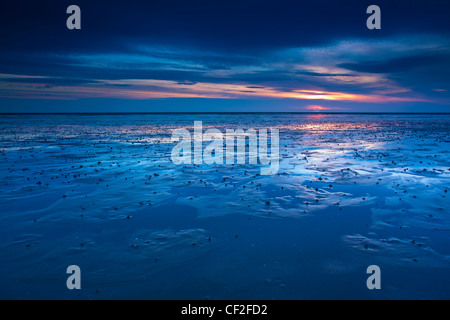 Les tons de bleu de l'aube reflétée sur la plage étendue de la plage de sables bitumineux Goswell le long de la côte du patrimoine de Northumberland. Banque D'Images