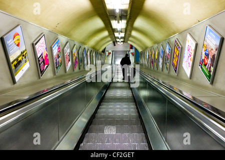 Un homme voyageant vers le bas un escalator dans une station de métro de Londres. Banque D'Images