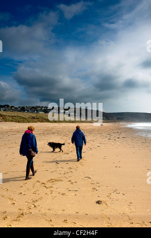Un couple en train de marcher leur chien sur Praa Sands. Banque D'Images