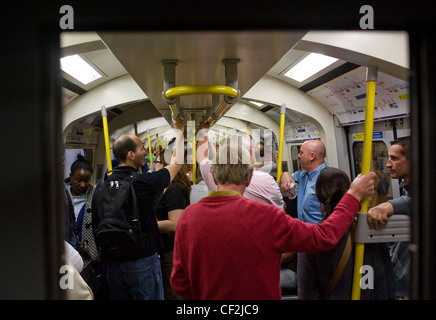 Les banlieusards emballés à l'intérieur du wagon d'un train de tube sur le métro de Londres. Banque D'Images