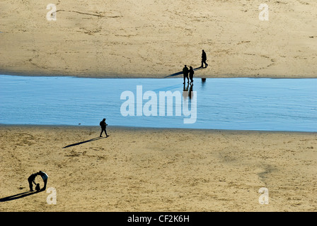 Silhouettes de personnes marchant sur la plage de sable de Dunraven Bay. Banque D'Images