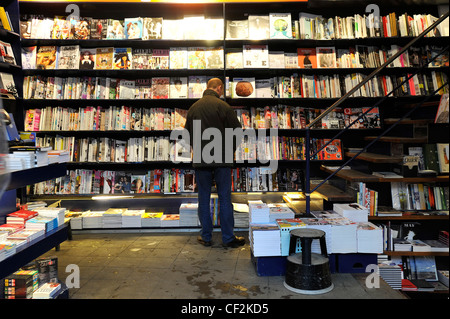 Un homme lit un magazine dans une librairie à Amsterdam, Pays-Bas. Banque D'Images