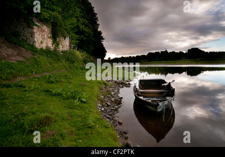 Un bateau à rames en bois amarré sur la rivière Tweed par Norham Castle, l'un des plus importants châteaux de la frontière et la plupart des Banque D'Images