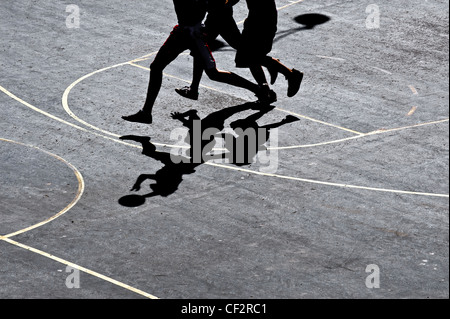 Ombres projetées sur une cour par des joueurs de basket. Banque D'Images