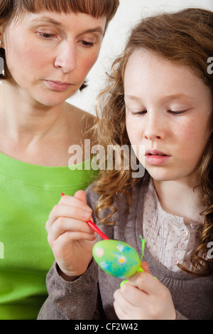 Mère et fille assis ensemble, à la maison et la peinture des oeufs de pâques Banque D'Images
