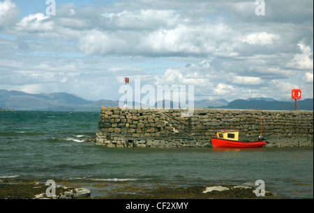 Un petit bateau amarré rouge par le mur du port à Broadford sur l'île de Skye. Banque D'Images