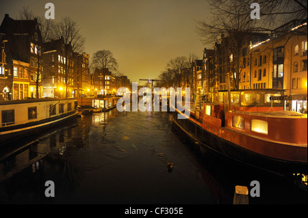 Houseboats de nuit sur un canal gelé à Amsterdam, Pays-Bas pendant l'hiver froid de février 2012. Banque D'Images