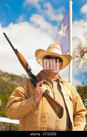 Cowboy d'âge moyen avec arme à feu en face du Texas flag Banque D'Images
