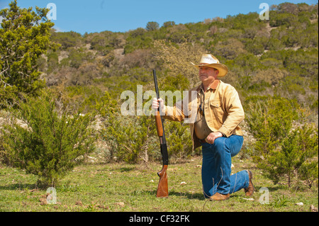 Texas cowboy avec fusil à genoux Banque D'Images