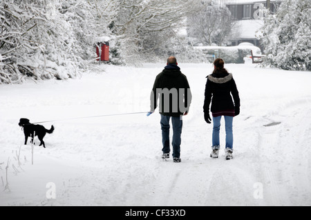 Marcher dans la neige le long de routes de campagne, couple matin dog walk après les fortes chutes de neige Brentwood Essex England UK Banque D'Images