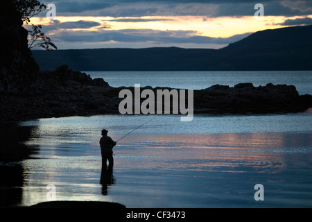 Un pêcheur de mouche au Loch Eishort au crépuscule sur l'île de Sky. Banque D'Images