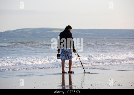 Un homme la détection de métal sur le bord de la mer à Bournemouth. Banque D'Images