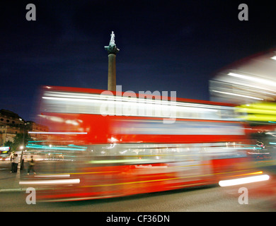 Trafalgar Square la nuit comme un bus rouge va passé dans le centre de Londres. Banque D'Images