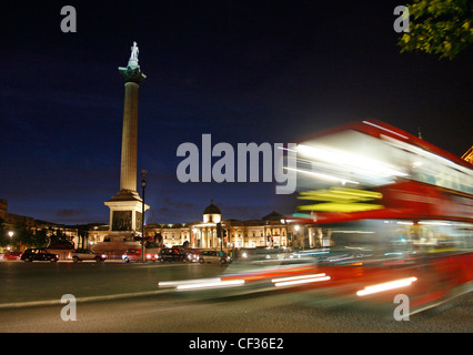 Trafalgar Square la nuit comme un bus rouge va passé dans le centre de Londres. Banque D'Images