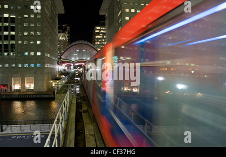 Docklands Light Railway train approchant vers Canary Wharf gare de nuit. Banque D'Images