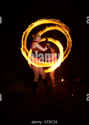 Une vue de nuit de deux femmes spinning fire poi à Hove dans l'East Sussex. Banque D'Images