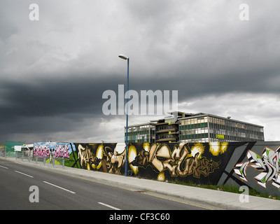 Graffitis sur les panneaux en face d'un bâtiment de style années 60, avec des nuages gris au-dessus de la région de Brighton. Banque D'Images