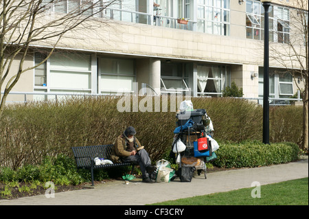 Sans-abri assis sur un banc, lisant un livre, Vancouver, British Columbia, Canada Banque D'Images