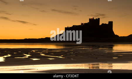 Une vue sur la silhouette de Château de Bamburgh, à l'aube. Le château est assis sur un affleurement de basalte sur le bord de la mer du Nord à un Bamburgh Banque D'Images