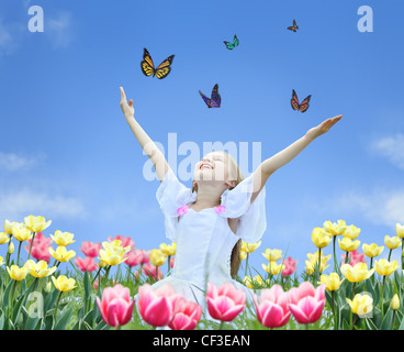 Petite fille dans les tulipes avec les mains en l'air et collage papillon Banque D'Images