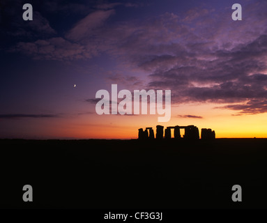 Un large paysage de la Stonehenge trilithons silhouetté après le coucher du soleil et de la lune. Banque D'Images