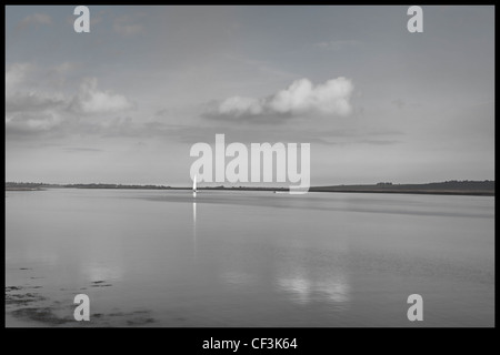 Yacht à voile blanc unique dans la distance sur une très vaste étendue de la rivière Crouch. Banque D'Images