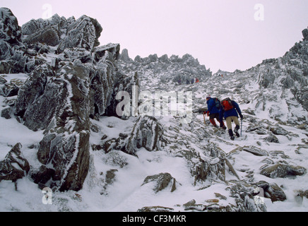 Les marcheurs dans la neige et la glace en suivant le chemin jusqu'au nord de Glyder Fach dans le parc national de Snowdonia. Banque D'Images