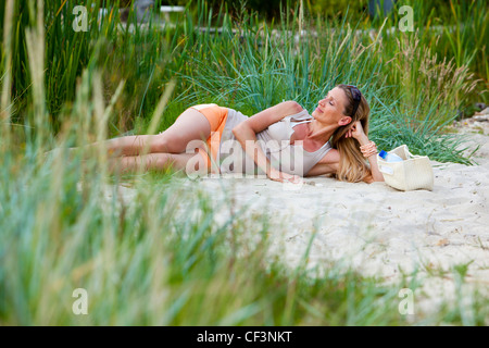 Smiling woman lying on beach Banque D'Images