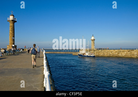 Un bateau naviguant entre l'Est et l'Ouest Pier phares sur son chemin hors de Whitby Harbour. Banque D'Images