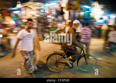 Un vieil homme d'une bicyclette à travers les rues bien éclairées de Marrakech Banque D'Images