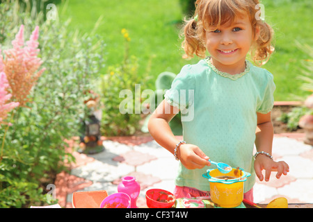 Smiling little girl joue cook in garden Banque D'Images