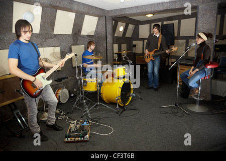 Un groupe de rock. chanteur girl, deux musiciens avec guitares électro et un batteur travaille en studio Banque D'Images