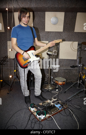 Homme avec electro guitare est le jeu près de l'appareil multi-effets guitare. L'accent sur les jambes Banque D'Images