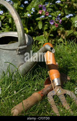 Arrosoir, la fourche et truelle sur un jardin pelouse. Banque D'Images