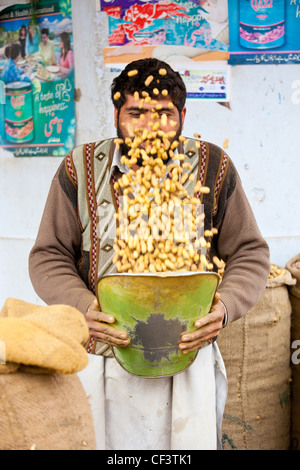 Vendeur dépose de l'écrou de coquilles lâche des arachides, Islamabad, Pakistan Banque D'Images