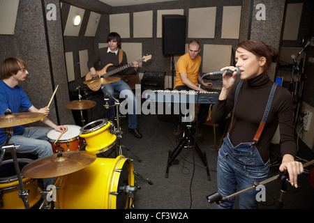 Un groupe de rock travaillant en studio. chanteur fille chante. L'accent sur clothers fille du chanteur Banque D'Images