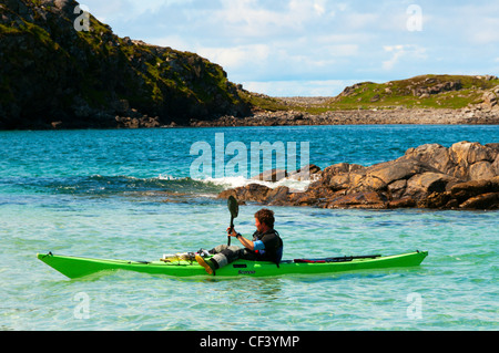 Un homme kayak hors de Camas Bostadh sur Great Bernera dans les Hébrides extérieures. Banque D'Images