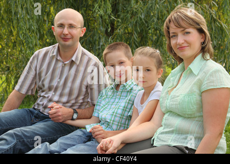 Famille avec deux enfants assis à l'herbe au début de l'automne parc. se concentrer sur le visage de petite fille Banque D'Images