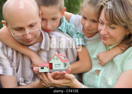 Famille avec deux enfants est de garder wendy house dans leurs mains et à le regarder. se concentrer sur wendy house. visages dans des problèmes de mise au point. Banque D'Images
