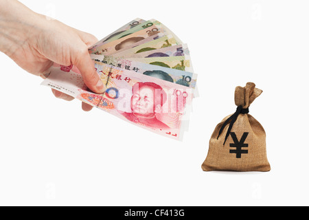 De nombreuses factures Yuan chinois avec le portrait de Mao Zedong sont tenue à la main. Près de par l'argent est un sac avec un Yen japonais Banque D'Images