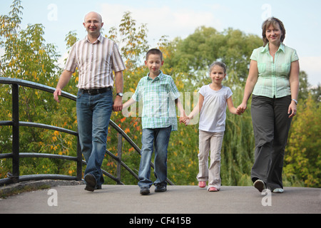 Famille avec deux enfants est de marcher sur le pont au début de l'automne parc. famille est handies. Banque D'Images