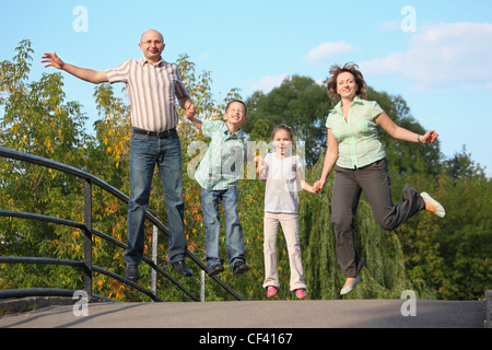 Famille heureuse avec deux enfants est de sauter sur un pont. famille est handies. Banque D'Images