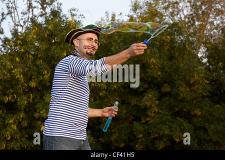 L'homme joyeux avec drawed barbe et moustache en costume pirate souffle des bulles de savon. Banque D'Images