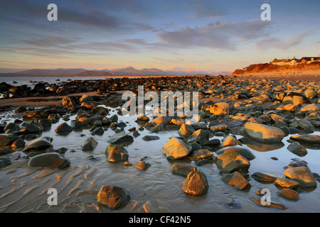 Coucher du soleil sur la plage jonchée de plus audacieux à Llanganwg avec la péninsule de Lleyn au loin. Banque D'Images