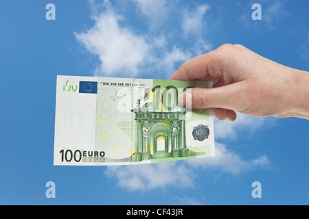 Une loi de 100 euros est tenue à la main. Le 01 janvier 2002, l'euro a été introduit comme argent comptant. Ciel est dans l'arrière-plan. Banque D'Images