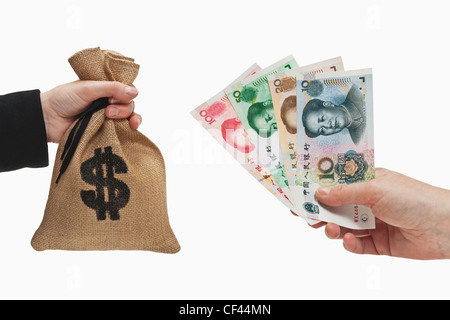 Divers projets de Yuan chinois sont tenue à la main. De l'autre côté d'un sac d'argent avec une monnaie Dollar américain s'est tenue à la main Banque D'Images