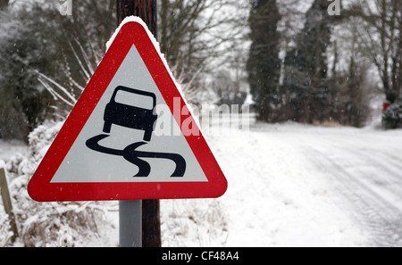 Une route glissante rural signer avec une route couverte de neige dans l'arrière-plan dans l'Essex. Banque D'Images