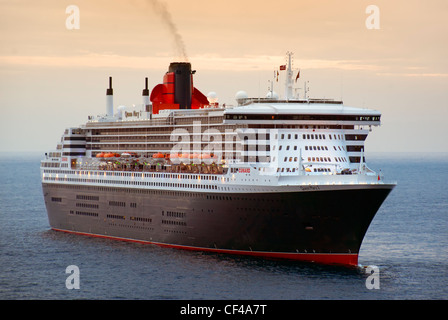 RMS Queen Mary 2, le plus grand paquebot jamais construit, au large du port de Monaco au crépuscule. Banque D'Images