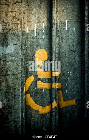 Symbole de la personne en fauteuil roulant peint sur une sombre, vieux, vieux mur de pierre. Banque D'Images